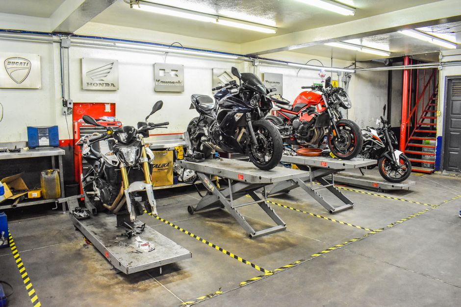 Technicien penche sur le moteur ouvert d une moto en atelier, outils disposes autour